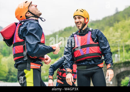 Lachen Freunde in Schutzkleidung am Fluss Ufer Stockfoto