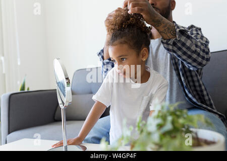 Vater tun Haare's Tochter auf der Couch zu Hause Stockfoto