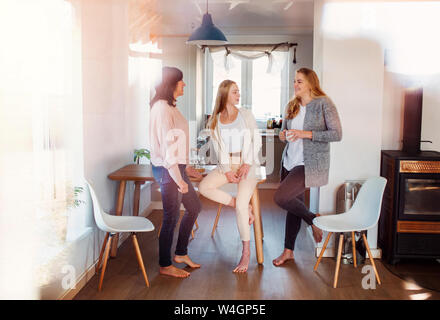 Mutter und Töchter stehen in der Küche, reden, trinken Kaffee Stockfoto