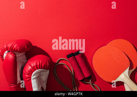 Blick von oben auf die Boxhandschuhe in der Nähe von red Ping pong Schläger und Springseil rot Stockfoto