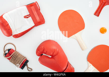 Blick von oben auf die Boxhandschuhe in der Nähe von red Ping pong Schläger und Springseil isoliert auf weißem Stockfoto