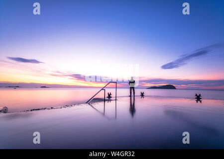 Mann, allein auf den Hafen Pier den Sonnenuntergang beobachten, North Berwick, East Lothian, Schottland Stockfoto