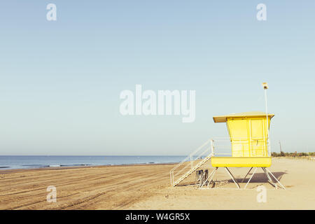 Sommer Szene mit einem bunten Gelb lifeguard Tower am Strand, bei Sonnenuntergang mit klarem Himmel im Hintergrund, kopieren Platz für Text Stockfoto