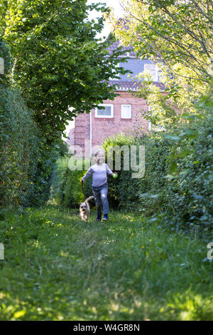 Kleines Mädchen auf einer Wiese mit ihrem Mischling Stockfoto