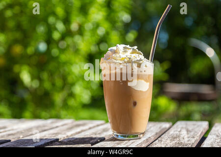 Glas Eiskaffee mit Sahne Topping auf Garten Tisch Stockfoto