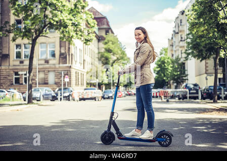 Porträt der lächelnde Frau mit E-Scooter in der Stadt Stockfoto