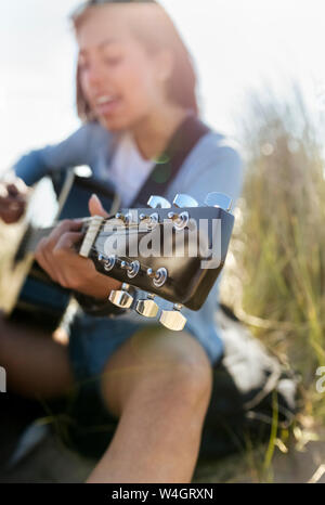 Nahaufnahme der jungen Frau singen und Gitarre spielen am Strand