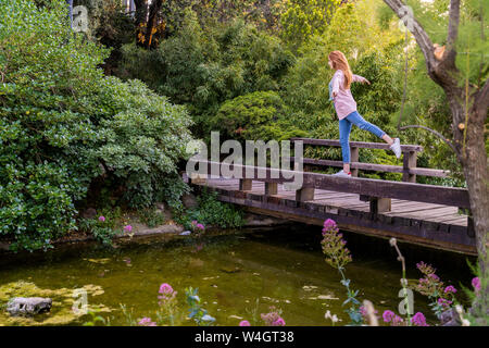 Junge rothaarige Frau Balancieren auf Brücke in einem Park Stockfoto