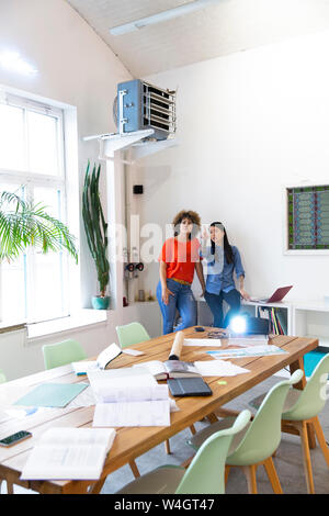 Zwei Frauen diskutieren in modernen Büro mit Videoprojektor auf Tisch Stockfoto