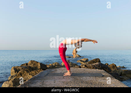 Junge Frau Yoga am Strand, einen Hintergrund Stockfoto