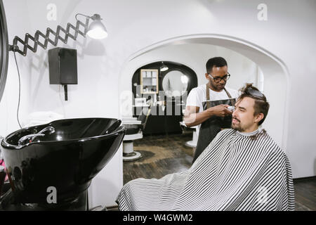 Friseur Rasieren und Kürzen von Haaren von einem Kunden in Friseur Stockfoto