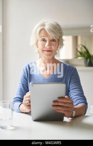 Portrait von lächelnden reife Frau mit digitalen Tablet am Schreibtisch Stockfoto