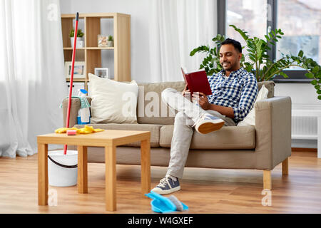Mann lesen Buch und Ausruhen nach Hause Reinigung Stockfoto