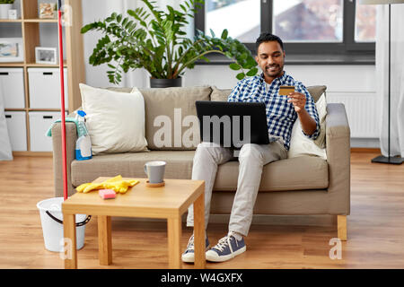 Mann mit Laptop online Einkaufen nach der Reinigung Stockfoto