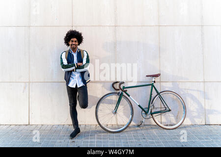Portrait von lächelnden casual Geschäftsmann mit Fahrrad stehend an der Wand Stockfoto
