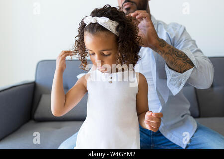 Vater tun Haare's Tochter auf der Couch zu Hause Stockfoto