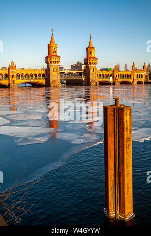 Blick auf die Oberbaumbrücke bei Sonnenuntergang mit frozen Spree im Vordergrund, Berlin, Deutschland Stockfoto