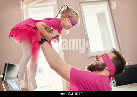 Vater und Tochter spielen Superhelden und superwoman, vortäuschen zu fliegen Stockfoto