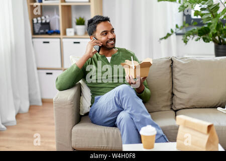 Lächelnd Inder essen Essen zum Mitnehmen zu Hause Stockfoto