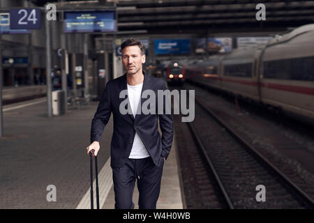 Reifer Mann mit Trolley auf Station Stockfoto