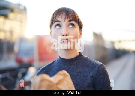 Porträt der jungen Frau mit Pommes Frites Schnurrbart schmollend Mund Stockfoto