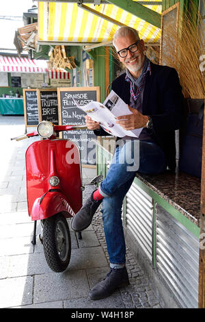 Reifer Mann auf dem Markt warten, Lesen Broschüre Stockfoto