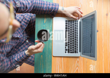 Mann, Pyjama sitzen mit Tasse Kaffee vor dem Laptop Stockfoto