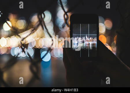 Nahaufnahme der Frau unter Smartphone Bild der Skyline bei Nacht, Manhattan, New York City, USA Stockfoto
