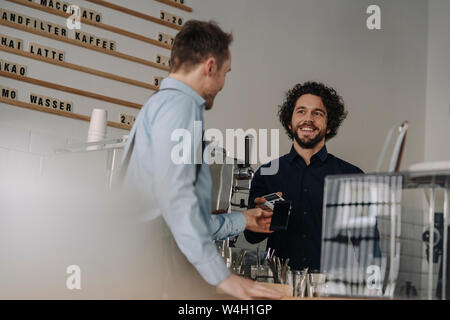 Kunden kontaktloses Bezahlen in einem Coffee Shop Stockfoto