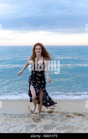 Porträt der glückliche junge Frau, die auf den Strand Stockfoto