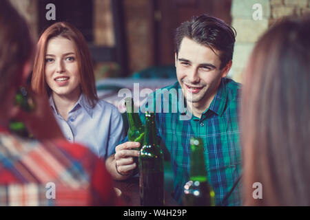 Freunde in einem Getränke in einer Bar, Sie sitzen an einem Holztisch mit Bier und Pizza Stockfoto