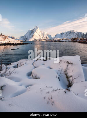 Haufen Schnee mit Fischerdorf in verschneiten Berg an der Küste. Lofoten, Norwegen Stockfoto