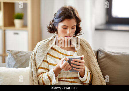 Traurig kranke junge Frau trinkt heißen Tee zu Hause. Stockfoto