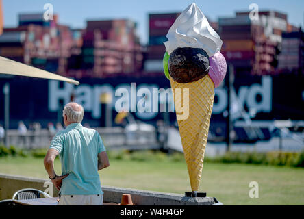 Hamburg, Deutschland. 23. Juli, 2019. Ein Mann beobachtet von einem Ice Cafe wie ein containerfrachter fährt entlang der Elbe. Quelle: Axel Heimken/dpa/Alamy leben Nachrichten Stockfoto