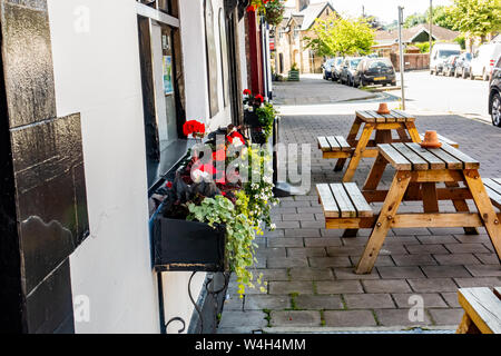 Blumentöpfe und Blumenkästen, zusammen mit Bänke im Freien entlang der High Street von Llanidloes, Mid Wales, Großbritannien Stockfoto