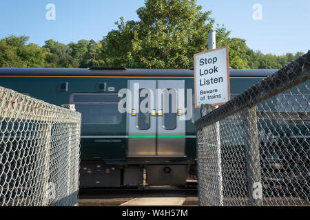 Pfad Überqueren einer Eisenbahnstrecke mit einem vorbeifahrenden Zug mit einer Sicherheits-Warnzeichen, Stop Look Listen, passen von Zügen, Großbritannien Stockfoto