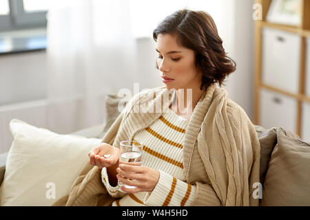 Kranke Frau, die Medizin mit Wasser zu Hause Stockfoto