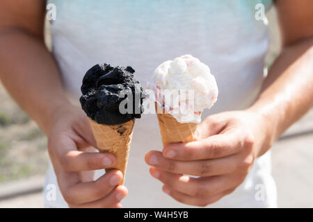 Ein junger Mann hält zwei Eistüten in seinen Händen. Stockfoto