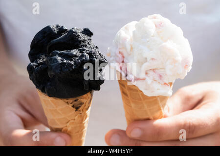 Ein junger Mann hält zwei Eistüten in seinen Händen. Stockfoto