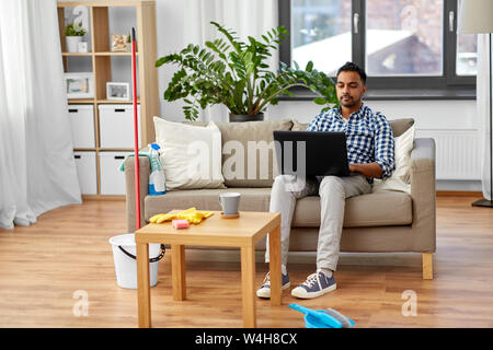 Mann mit Laptop nach Hause Reinigung Stockfoto