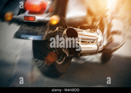 Auf der Asphaltstraße in der Stadt schnell reitet eine kühle schöne schwarze Motorrad mit roten Lichtern, die durch Sonnenlicht beleuchtet. Stockfoto