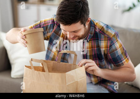 Lächelnd Mann auspacken Essen zum Mitnehmen zu Hause Stockfoto