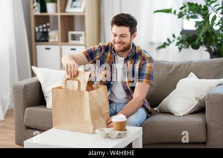 Lächelnd Mann auspacken Essen zum Mitnehmen zu Hause Stockfoto