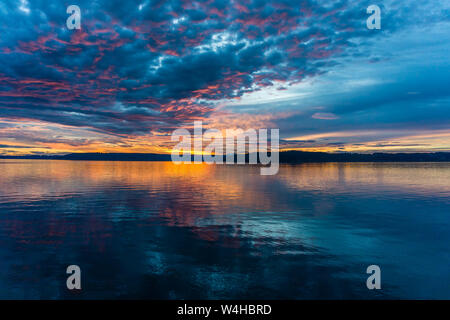 Die Wolken hängen am Himmel, wie die Sonne hinter den Olympic Mountains im Armaturenbrett, Washington. Stockfoto