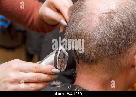 Frau Friseur schneidet die Haare des Mannes mit elektrischer Haarschneider Trimmer Stockfoto