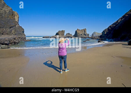 Eine teourist nimmt ein Foto auf den Pazifischen Ozean mit Ihrem Iphone in der Nähe von Lincoln City, Oregon, auf der Oregon Pazifikküste. Stockfoto