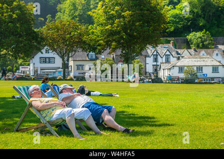 Hafen von Lynmouth, North Devon, England. Dienstag, den 23. Juli 2019. UK Wetter. Mit steigenden Temperaturen unter blauem Himmel, Urlauber genießen genießen Sie die Sonne im Kleinen Park neben dem malerischen Hafen von Lynmouth in North Devon. Credit: Terry Mathews/Alamy leben Nachrichten Stockfoto