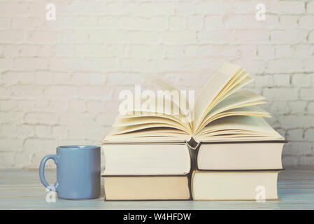 Stapel von Büchern mit Tasse Kaffee auf hölzernen Tisch Stockfoto