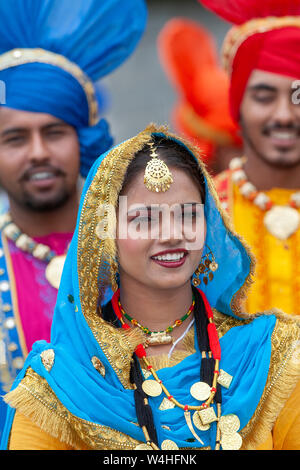 Lächelnd indische Frau das Tragen der traditionellen indischen nationalen Kleid. Zwei lächelnde Männer hinter Stockfoto