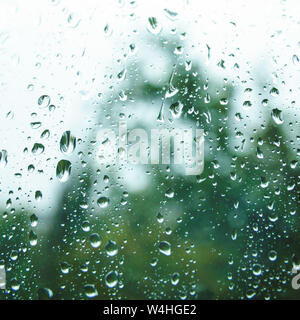 Wassertropfen an regnerischen Tag auf außen Fenster Glas mit unscharfen Rändern. Regentropfen auf der Fensterscheibe im Sommer Tag. Regen vor dem Fenster im Sommer Tag. Stockfoto